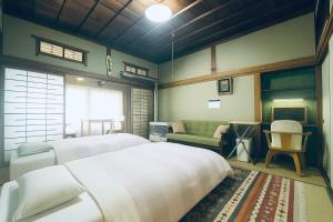 a bedroom with two white beds and a couch at Ryokan Sansui in Furano