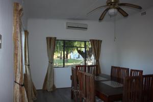 a dining room with a table and chairs and a ceiling fan at Papkuilsvlei Selfsorg Plaashuis in Muishondfontein