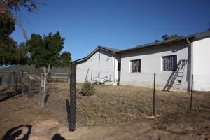 a fence in front of a white house at Papkuilsvlei Selfsorg Plaashuis in Muishondfontein