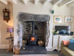 a stone fireplace in a living room with a tv at 1 Penygroes in Penmachno