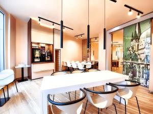 a dining room with a white table and chairs at B&B Hotel Aachen-City in Aachen