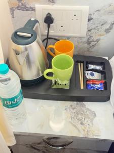 a tray with a tea pot and cups on a counter at THE PRINCE Hotel in Kharagpur