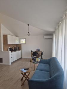 a living room with a blue couch and a kitchen at Seaview Art Studio with balcony in Kaštela