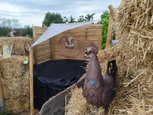 a large brown chicken laying on hay next to a wooden house at Lodge romantique "esprit brocante" et son jacuzzi privatif in Lapalisse +3 photos