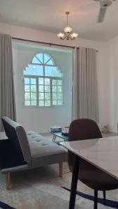 a living room with a table and chairs and a window at Qantab village apartment in Muscat