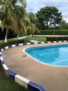 a large swimming pool in a yard with palm trees at Casa campestre con piscina, jacuzzi y bbq in La Dorada