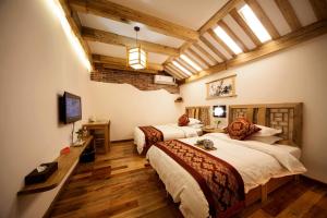 two beds in a room with wooden floors at Zhangjiajie Wangyi Inn in Zhangjiajie