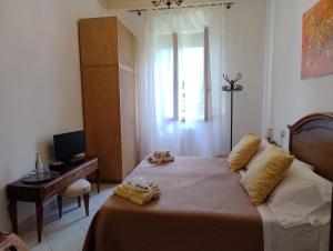 a bedroom with a bed with a desk and a window at MARIA HOLIDAY HOMES La Pineta di Sinalunga in Sinalunga