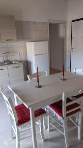 a white table and chairs with two red candles on it at La casa di Erica in Sestu +10 photos