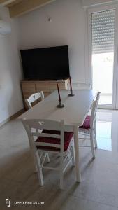 a white dining room table with two chairs and a tv at La casa di Erica in Sestu