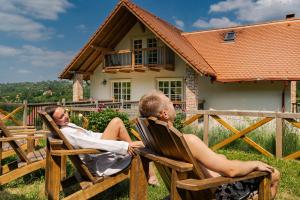 two men sitting in rocking chairs in front of a house at The Lodge Transylvania in Bran