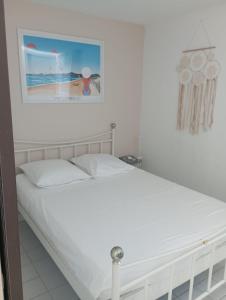 a white bed in a bedroom with a picture on the wall at Marina St Cyprien in La Celle-sous-Gouzon