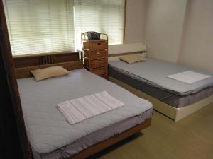 Private Retreat Nagasaki Vogelnest 2階貸切屋上テラス貸切長崎スタジアム5分 في ناغاساكي: غرفة نوم بسريرين وخزانة ونافذة