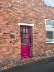 a red door on the side of a brick building at 2 Newcastle Street in Crewe