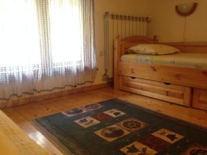 a bedroom with a bed and a rug and a window at Tipografov View Guest House in Veliko Tŭrnovo