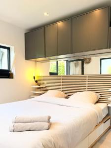 a bedroom with a large white bed with black cabinets at La Suite (Ô) Wood & Chic in Cucq