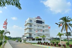 a hotel on the side of a road with palm trees at Oasis Service Apartments in Mysore