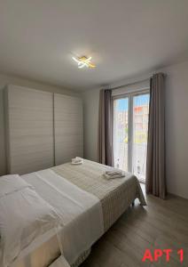 een slaapkamer met een wit bed en een raam bij Agnese Apartments in Diano Marina