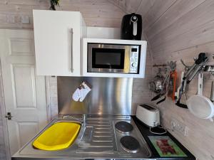 une petite cuisine avec une cuisinière et un micro-ondes dans l'établissement Coastal Cabin Oldshoremore, à Rhiconich