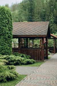 a wooden gazebo with a roof in a garden at Domik Zubanicha in Kelechin