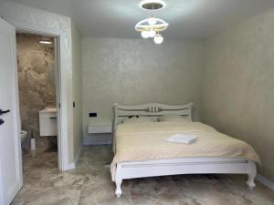 a bedroom with a white bed and a chandelier at Domik Zubanicha in Kelechin +3 photos