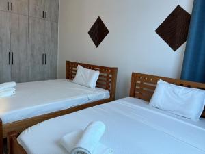 two beds in a small room with white sheets at Deanway homes in Mombasa +13 photos