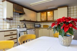a kitchen with a table with red flowers in a vase at Killard Farm in Bellaghy