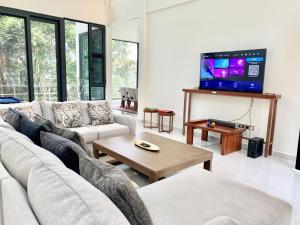 Deco Home The Summit Mesilau at Kundasang في Kampong Kundassan: غرفة معيشة مع أريكة وتلفزيون