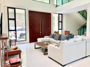 Deco Home The Summit Mesilau at Kundasang في Kampong Kundassan: غرفة معيشة مع أريكة بيضاء وطاولة