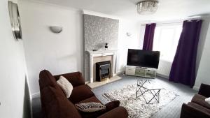 a living room with a couch and a television at Family friendly 3-bed home free parking on site in Huddersfield