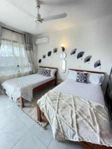 a bedroom with two beds and a window at Mambo Sea view 3bd Penthouse Mombasa in Mombasa