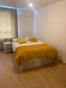 Un dormitorio con una cama con una manta amarilla encima. en Ellison House, en Londres