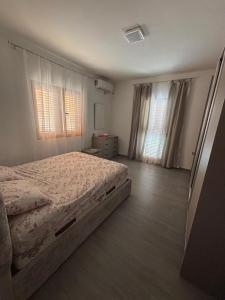 a bedroom with a bed and two windows at Albert's house for rent in Vlorë