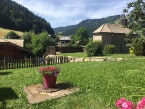 a yard with a pot of flowers in the grass at Le Château - Appartement Génépi in Morzine +7 photos
