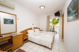 1 dormitorio con cama, escritorio y espejo en Astali Hotel, en Rethymno