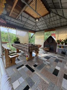 ein großer Raum mit einem Tisch und Bänken auf einem gefliesten Boden in der Unterkunft Secret garden in Visoko