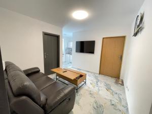 ein Wohnzimmer mit Ledersofa und einem Tisch in der Unterkunft PENZION Hamburk in Beroun