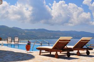a pair of chairs sitting next to a swimming pool at Pyrgos Zante Suites in Alikanas