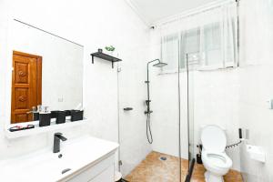 Un baño blanco con ducha y WC. en kigali Pillar House inn, en Kigali