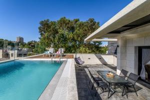a swimming pool with a table and chairs next to a house at Penthouse with pool jerusalem in Jerusalem