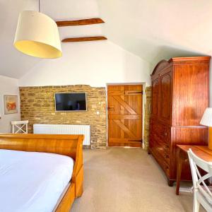 a bedroom with a bed and a wooden cabinet and a tv at Whitley Coach House in Whitley