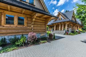 une maison en rondins avec un chemin devant elle dans l'établissement Osada nad potokiem, à Kościelisko