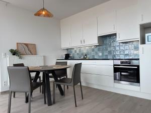 a kitchen with a table and chairs and white cabinets at Beach Addict Appartment Duinrust in Knokke-Heist +7 photos