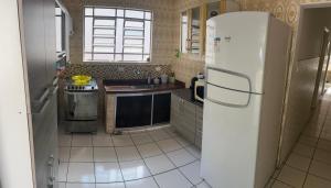 a kitchen with a white refrigerator and a sink at Casa com Ar condicionado a 50m da praia de Riviera in Bertioga
