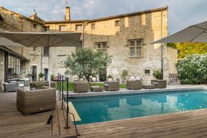 a pool with chairs and an umbrella next to a building at La Chapelle sur la Sorgue in L'Isle-sur-la-Sorgue