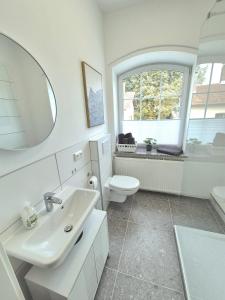 a bathroom with a sink and a toilet and a mirror at Studio 1 - Apartments am Schloss in Oberschleißheim