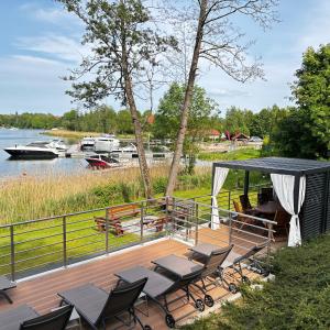 a deck with chairs and a gazebo next to a lake at Pratum Pink&Blue Apartament Glamour z widokiem na jezioro i wanną in Mikołajki +27 photos