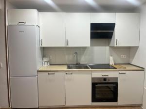 a kitchen with white cabinets and a stainless steel refrigerator at Navarubia in Navacerrada