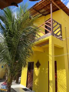 a yellow house with a palm tree in front of it at Sertão beach in Tutóia +5 photos