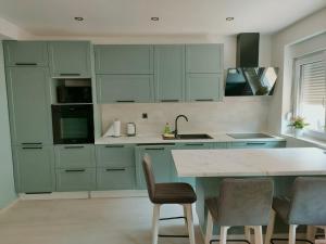 a kitchen with green cabinets and a counter with chairs at Apartman Fortis in Knin